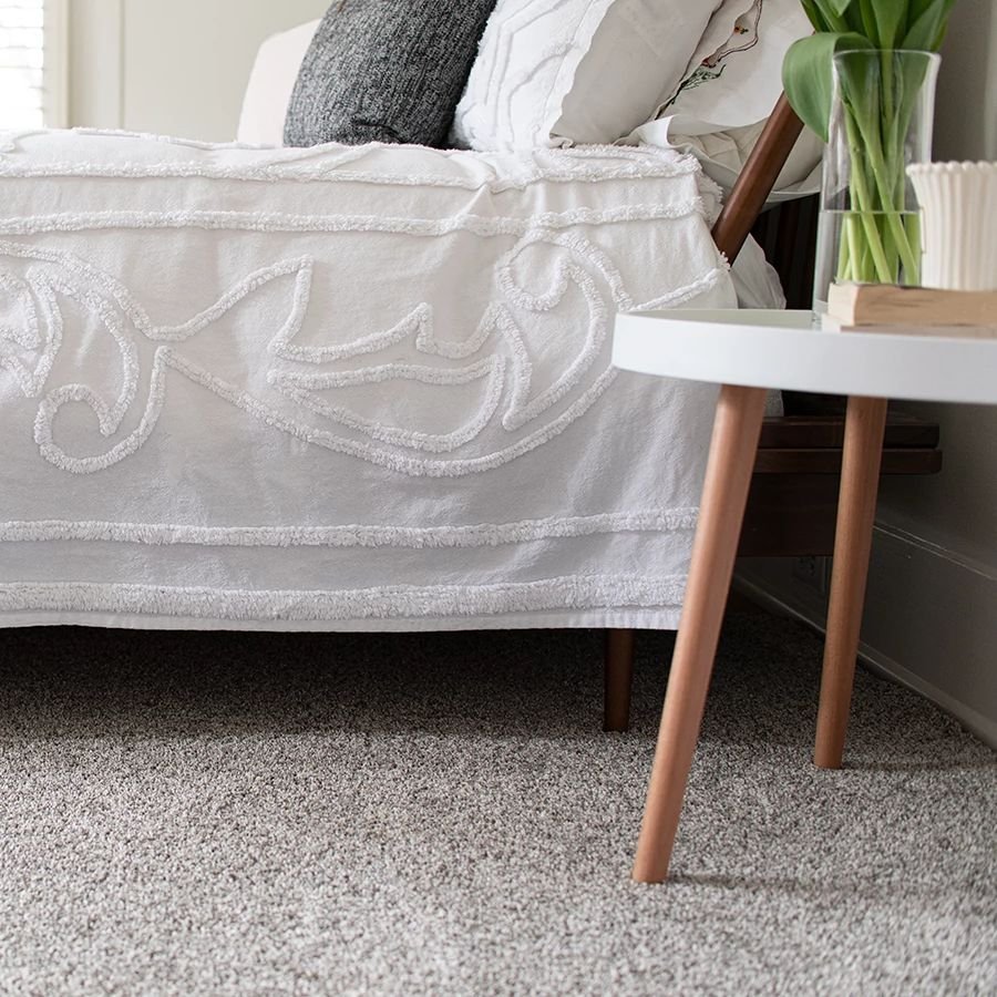 closeup of bed on carpet with night table - Economy Carpet Inc